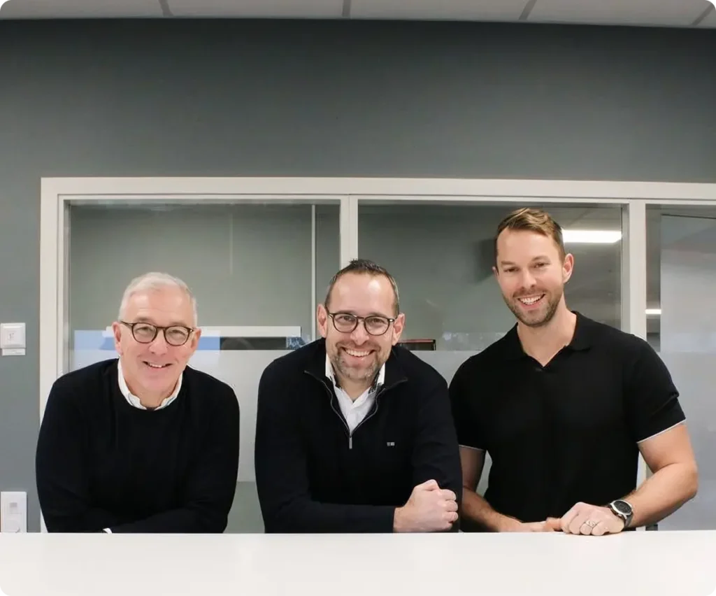 Three men smiling in an office.