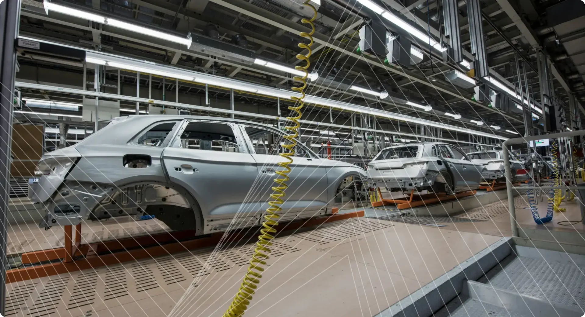Automotive production line with unfinished car bodies and industrial equipment inside a factory.